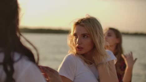 Three-female-students-are-dancing-and-enjoying-party-on-the-beach-with-beer.-They-move-their-young-bodies-and-long-hair.